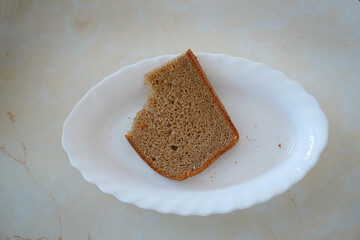 Half-eaten piece of rye bread on white plate