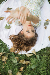 Naklejka premium Portrait of young woman with physical disability in stylish summer dress smiling sincerely in camera at green park. Female person who lies on the green grass enjoying summer weather outdoors.