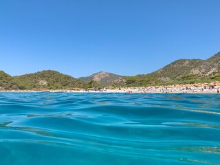 Birch, clear sea and mountains on the horizon. An ideal place for a seaside holiday. In the distance, a Mediterranean beach, view from the water. Turkey, Oludeniz, blue lagoon beach, August 10, 2021