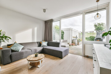 White colored living room with oriental rug furnished with gray sofa and rattan armchair