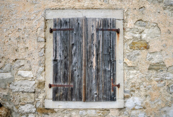 Fototapeta na wymiar Stone wall of old house and window with wooden shutters. Hum, Croatia