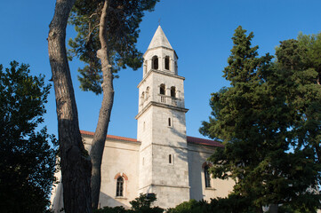 Fototapeta na wymiar Parish church of St Anastasia in small town Biograd na Moru in Croatia, surrounded with pine trees