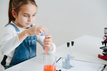 Patient little girl doing home science project, mixing two liquids in a flask