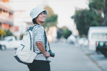 Travel concept, Asian woman tourist with backpacker relaxing on city streets, Portrait asian female backpacker wearing hat traveling carry digital camera retro picture style, Happy relax on holiday.