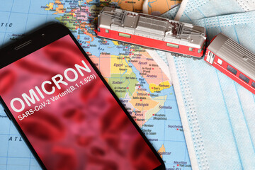 Omicron variant. Smartphone with 'Omicron' text on abstract defocused of red viruses with model...