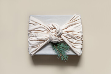 Christmas present in beige cotton fabric with spruce twigs. Traditional Japanese furoshiki style....