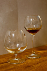 A glass of elite cognac on the bar. Wooden table background. Hard strong alcoholic drinks, spirits and distillates in glasses: vodka, cognac, tequila, scotch, brandy and whiskey, grappa, vermouth, rum