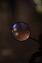 mirror view of a scooter in rainy conditions.