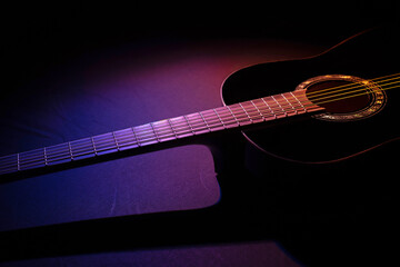 Obraz na płótnie Canvas black guitar against split colored background. guitar music dark shoot