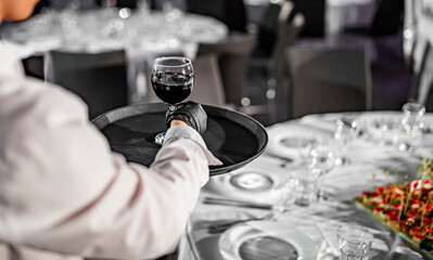 Waiter serving red wine glass in restaurant