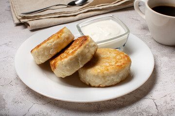 Cottage cheese cheesecakes, fried cheesecakes on a white plate. Cheesecakes on a light background