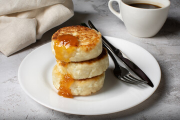 Cottage cheese cheesecakes, fried cheesecakes on a white plate. Cheesecakes on a light background