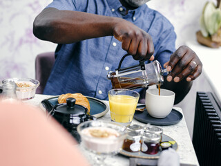 Fototapeta na wymiar Man pouring coffee at breakfast table