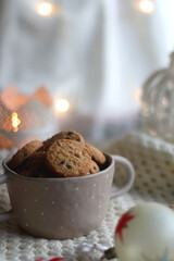 Bowl of cookies, soft knitted blanket and colorful Christmas ornaments at home. Selective focus.