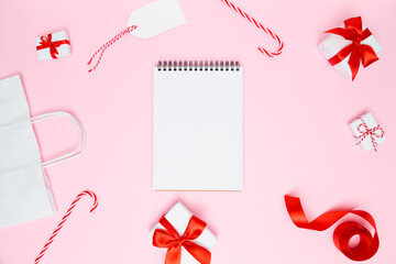 Christmas cozy background. Blank open notebook with festive decorations, gift boxes on pastel pink. Preparation for holidays. New year planning, goals, to-do list or wish list. Flat lay, copy space.