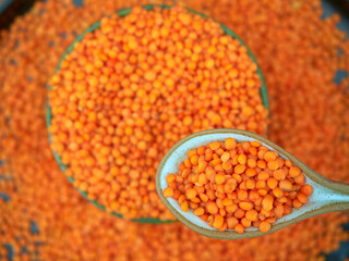 Red lentils in a green ceramic bowl, selective focus