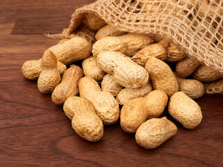Raw peanuts in a bag, uncooked, not salted. on a walnut table