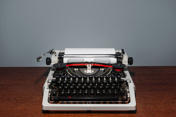Typewriter 70s with red printed ribbon without top cover on wood table and gray background