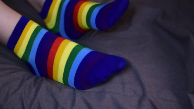 Wearing rainbow colored socks and jiggling the feet sitting in bed. Comfortable and funny piece of clothing