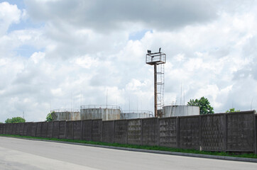 Fototapeta na wymiar Old dirty oil storage tanks behind the concrete fence