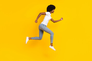 Fototapeta na wymiar Full length photo of cute adorable dark skin woman dressed white t-shirt smiling running jumping isolated yellow color background