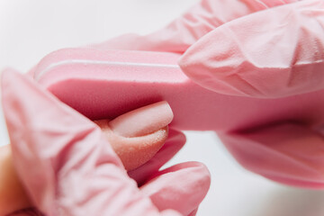 Manicure process. The master processes artificial nails with a nail file.
