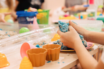 kinetic sand. children's hands play with multi-colored polymer sand.