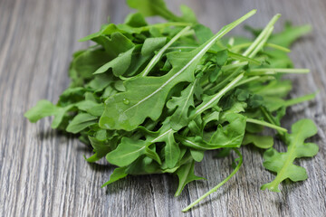 Close-up of fresh organic arugula leaves on a rustic wooden table.
Healthy food concept.