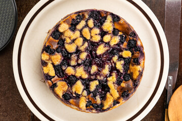 Top view of delocious homemade blueberry and crumble cheesecake in brown ceramic dish on wooden table