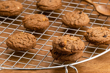 View of freshly baked delicious homemade chocolate chip butter cookies on cooling rack on wooden table.