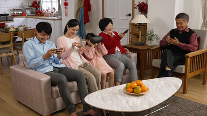 asian family members addictive to electronics are playing with smartphones, vr glasses and watching...