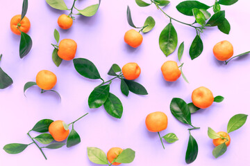 Mandarins with leaves on a lilac background. Flat lay, top view.