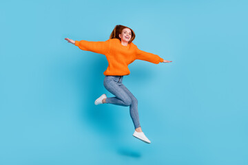 Fototapeta na wymiar Full body photo of young funny lady jump wear sweater jeans sneakers isolated on blue color background