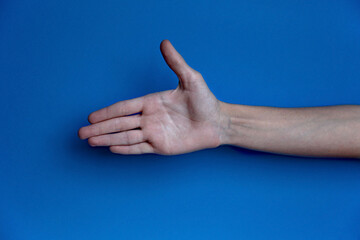 Palm of a person with a raised thumb smiley face on a blue background