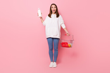 Full length photo of happy nice amazed woman hold hands grocery milk shop isolated on pink color background