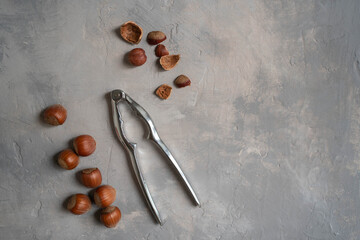 Hazelnuts with nutcracker on gray background. Top view of nuts.