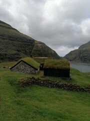 Traditional old cute stone houses with grass roofs on the Faroe Islands with a mountain view