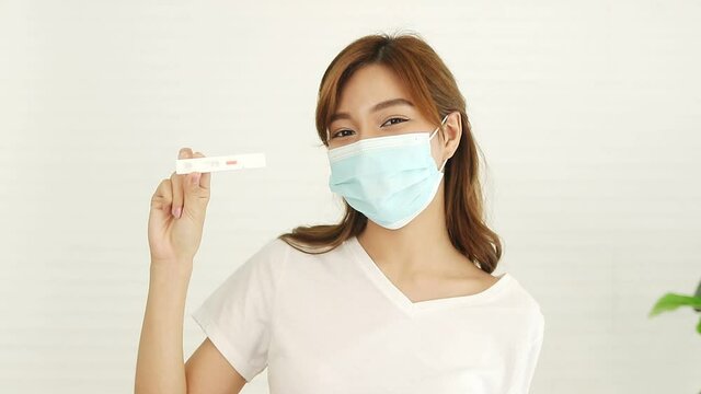 Beautiful Asian woman wearing a mask. Sick with the flu, stay at home, take the Covid-19 (Antigen Test) test by yourself, it's negative. concept of coronavirus protection