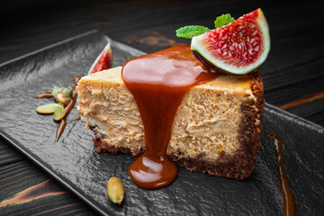 Cheesecake on a dark stone, wooden background, with mint and figs
