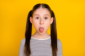 Photo of young school girl unhappy negative offended tongue-out isolated over yellow color...