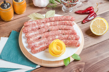 Semi-finished barbecue sausages on a white plate on a dark wooden background