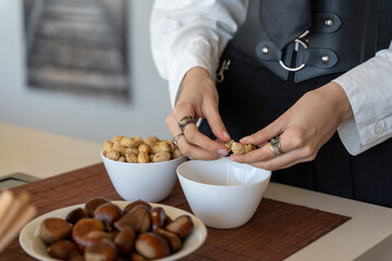 woman's hands peeling peanuts over a bowl in the kitchen