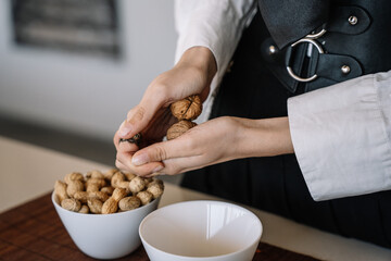 close-up view of a person cracking two walnuts with her hands