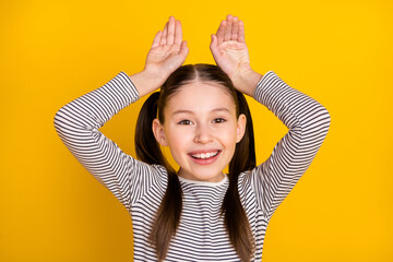 Photo of young girl happy positive smile grimace hold hands bunny ears rabbit isolated over yellow color background - obrazy, fototapety, plakaty