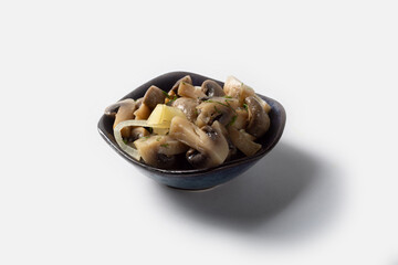 Pickled mushrooms with a dark plate on a white background under insulation