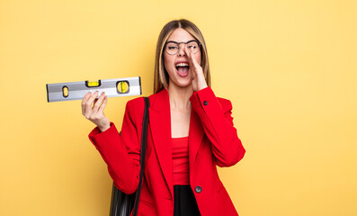 architect woman feeling happy,giving a big shout out with hands next to mouth and holding a level...