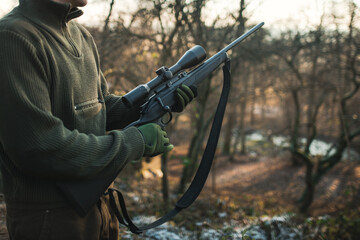 Professional hunter with hunting rifle. Man on the hunt in the middle of forest. Modern hunting...