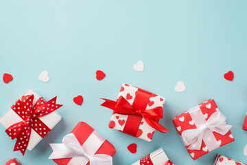 Fototapeta na wymiar Top view photo of st valentine's day decorations heart shaped confetti a lot of gift boxes in wrapping paper with heart pattern and bows on isolated pastel blue background with blank space