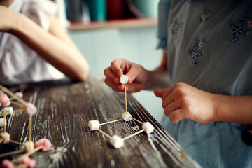 Children play with marshmallows and toothpicks, edible designer in the kitchen. Educational classes...