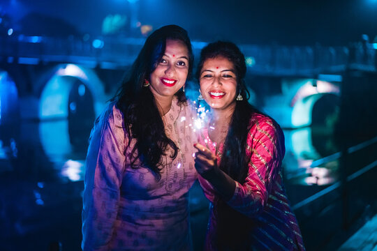 Two young Indian women smiling with bengal fireworks, celebrating. New Year Celebration. Indian Festival Diwali. Udaipur, Rajasthan, India. 